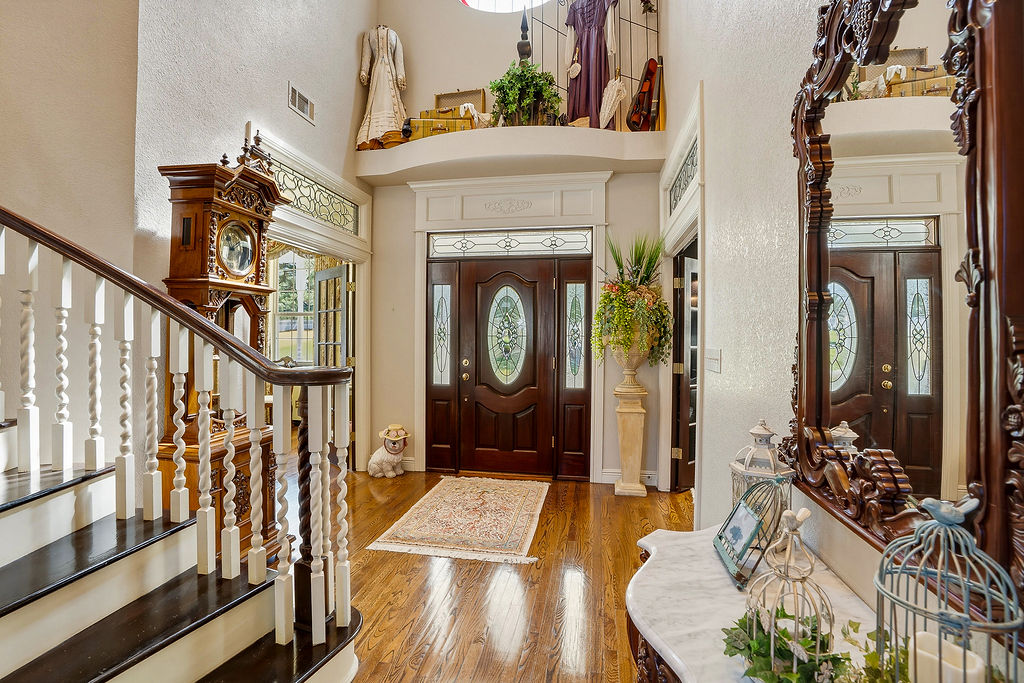 1009 Southeast County Road Ada, OK 74820 - Photo 11 of 92 Hardwood flooring, dark wood entry doors with oval glass inserts, and a staircase featuring white balusters and dark wood handrail