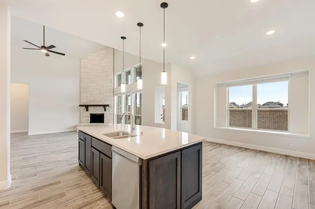 a open kitchen with kitchen island a sink appliances and a wooden floor