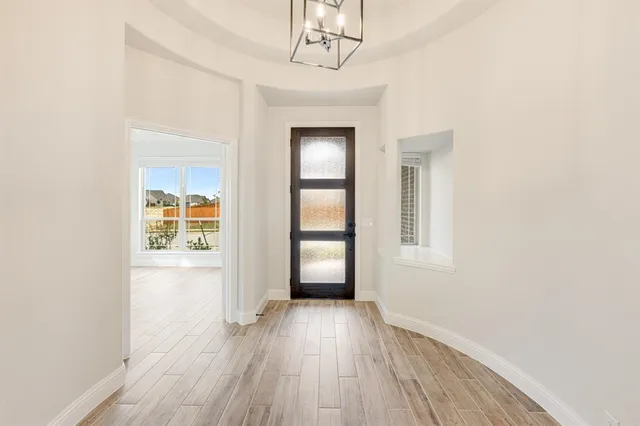 an empty room with wooden floor cabinet and windows