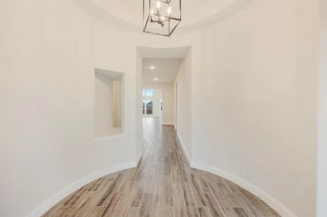 a view of a hallway with wooden floor and a chandelier