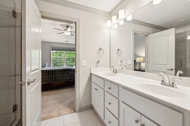 a en suite bathroom with a double vanity sink a large mirror a bathtub and window