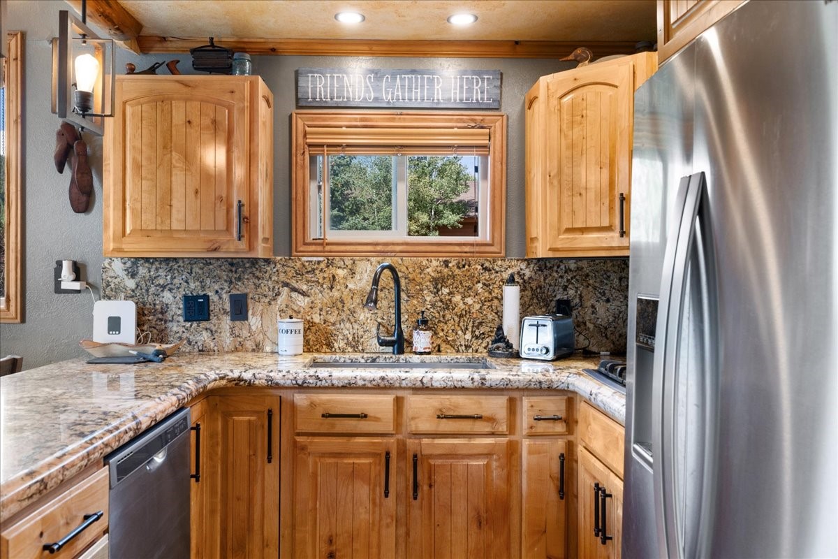 19 East Hanson Road Keystone, CO 80435 - Photo 7 of 24 Kitchen featuring stainless steel appliances, decorative backsplash, light stone countertops, a textured wall, and crown molding