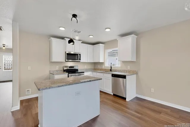 a kitchen with stainless steel appliances granite countertop a sink dishwasher a stove and a refrigerator with wooden floor