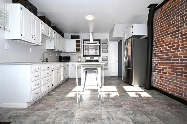 a kitchen with stainless steel appliances kitchen island granite countertop a stove a sink and a refrigerator