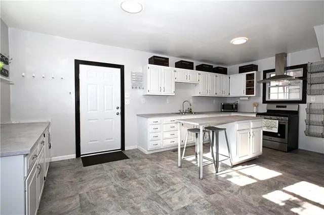 a kitchen with granite countertop a stove top oven and white cabinets