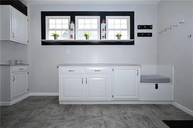 a view of kitchen with white cabinets and window