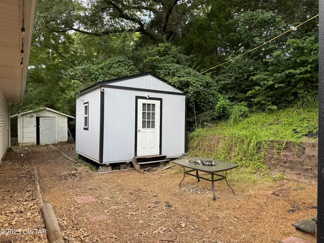 a white house that has a small yard and large trees