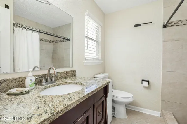 a bathroom with a granite countertop sink toilet and a mirror