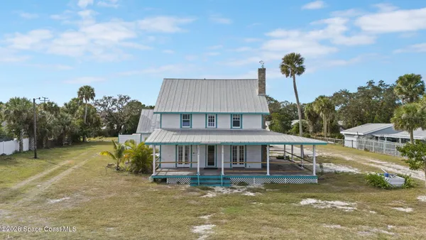 a aerial view of a house with a yard balcony and trees in the background
