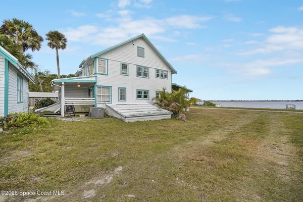 a front view of a house with a garden and lake view