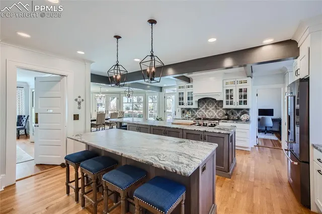 a large kitchen with granite countertop a stove a sink a refrigerator and wooden floor