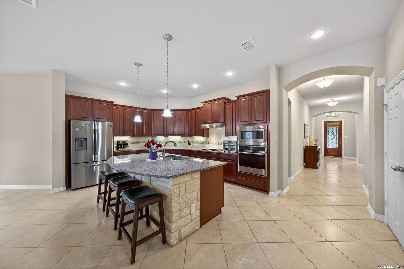 9108 Trail Stem Schertz, TX 78154 - Photo 9 of 26 a kitchen with stainless steel appliances kitchen island granite countertop a refrigerator oven a sink a dining table and chairs with white cabinets