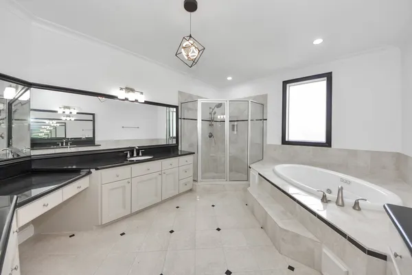 a large white bathroom with a large mirror vanity and a bathtub
