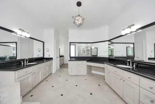a large white kitchen with a sink and dishwasher a oven with white cabinets