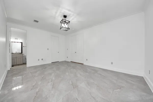 an empty room with a chandelier fan and windows