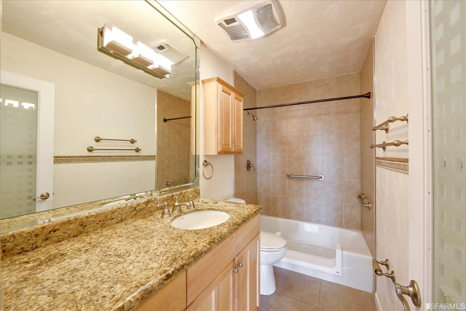 466 Crescent Street, Unit 310 Oakland, CA 94610 - Photo 18 of 24 a bathroom with a granite countertop sink a mirror and a shower