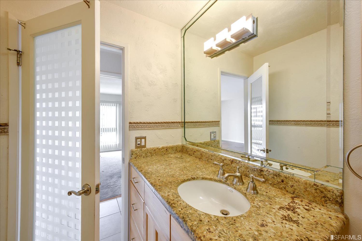 466 Crescent Street, Unit 310 Oakland, CA 94610 - Photo 19 of 24 a bathroom with a granite countertop sink and a mirror