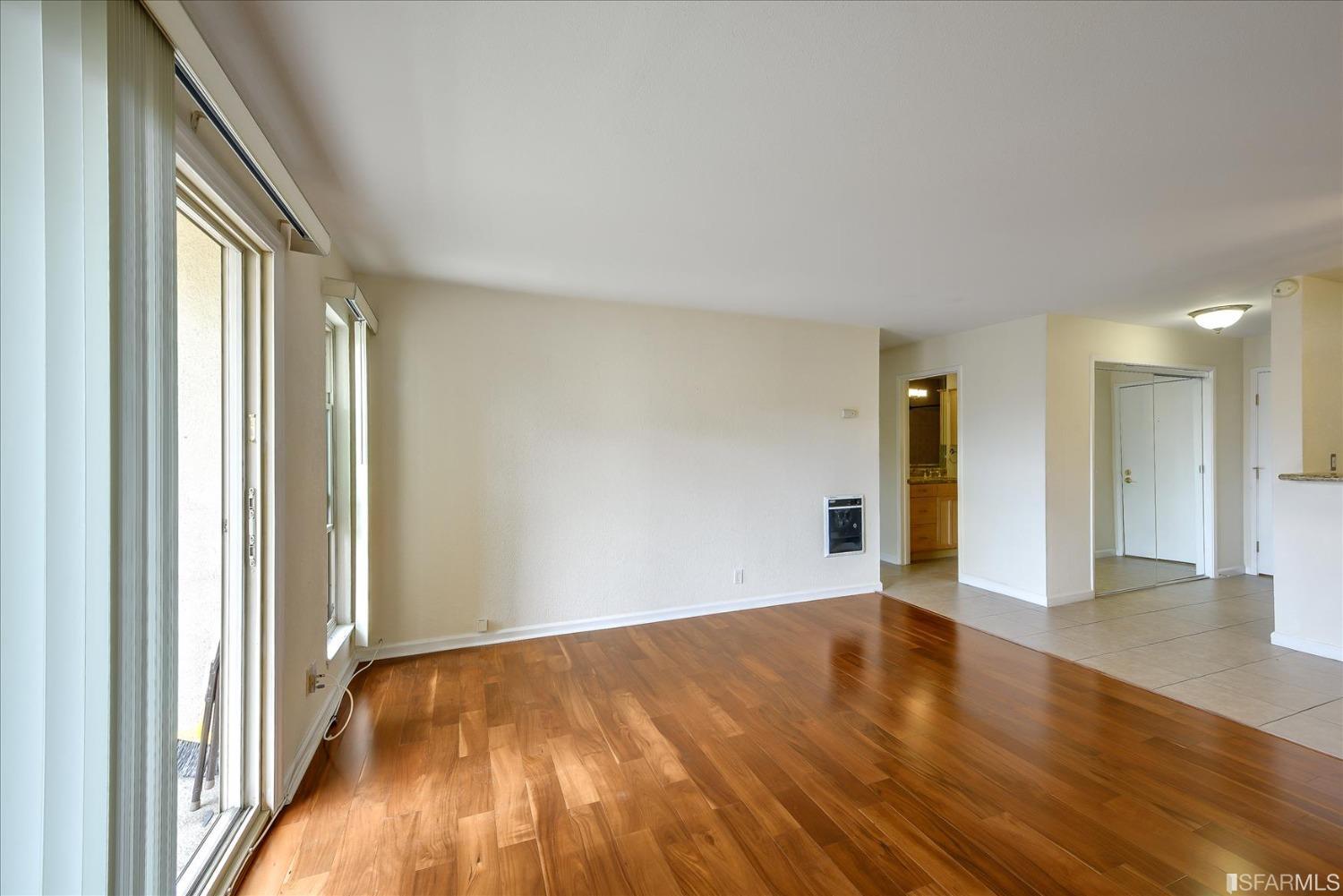 466 Crescent Street, Unit 310 Oakland, CA 94610 - Photo 7 of 24 a view of an empty room with wooden floor and a window