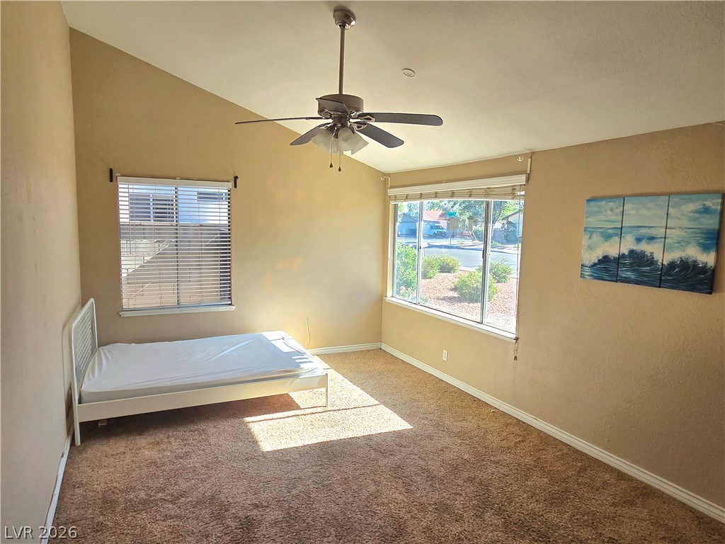 3648 Bronco Road Las Vegas, NV 89103 - Photo 6 of 24 A well-lit bedroom featuring vaulted ceilings and soft carpeting underfoot.