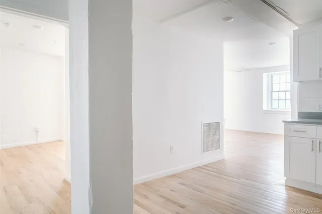 a view of hallway with window and wooden floor
