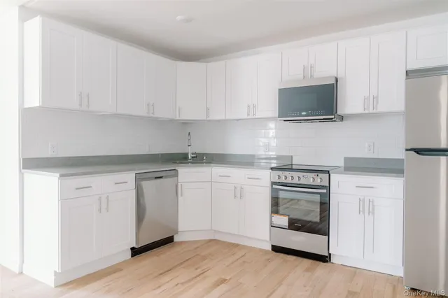 a kitchen with white cabinets and stainless steel appliances