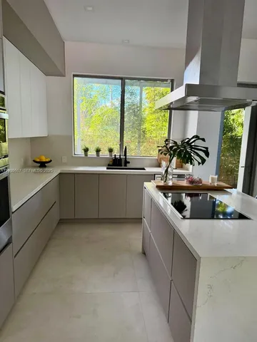 a large kitchen with stainless steel appliances a sink a stove and a window
