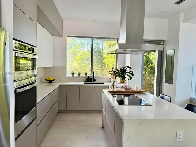 a kitchen with kitchen island a sink a counter top space and stainless steel appliances