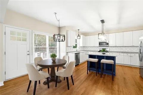 a dining room with wooden floor a chandelier a glass table and chairs