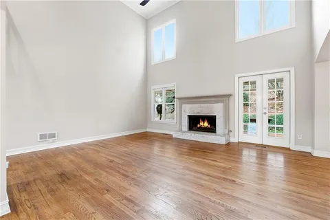 a view of an empty room with wooden floor fireplace and a window