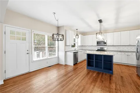 a open kitchen with wooden floors appliances and cabinets