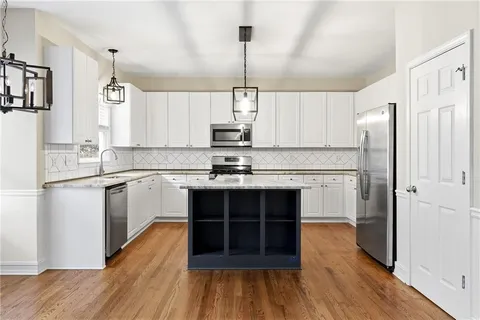 a kitchen with kitchen island granite countertop a stove a sink and a refrigerator with wooden floor