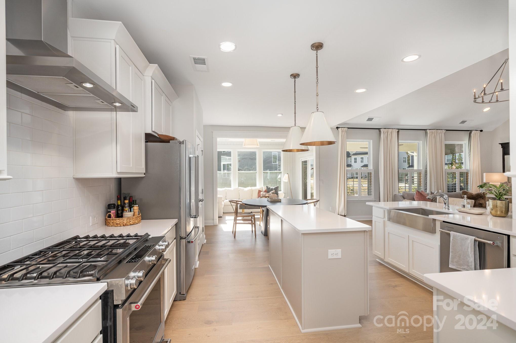 3063 Patchwork Court Fort Mill, SC 29708 - Photo 7 of 28 a kitchen with stainless steel appliances granite countertop a stove top oven a sink a dining table and chairs with wooden floor