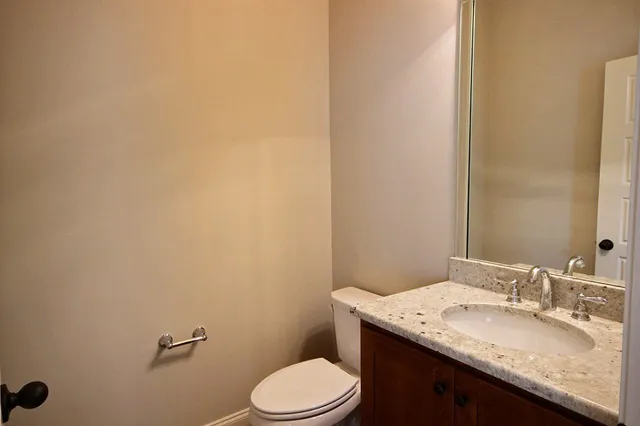 a bathroom with a granite countertop sink a toilet and mirror