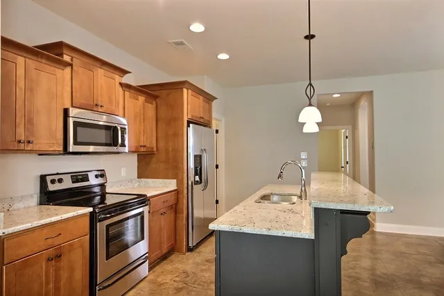 a kitchen with stainless steel appliances granite countertop a sink a stove and a refrigerator