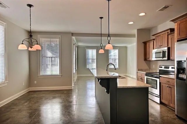 a kitchen with stainless steel appliances granite countertop a stove a sink a refrigerator a center island a dining table and chairs