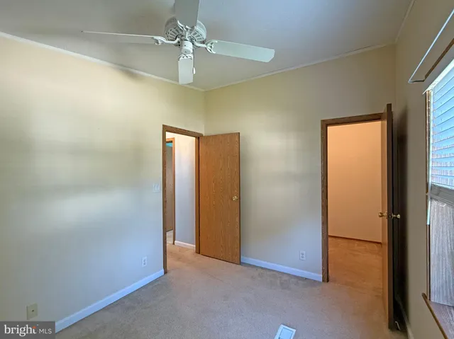an empty room with closet and a chandelier fan