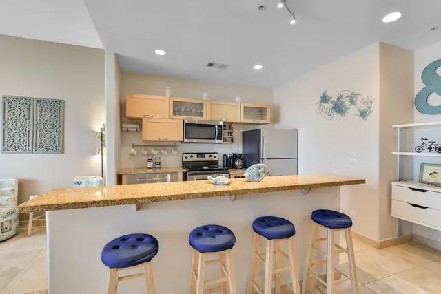 a kitchen with stainless steel appliances granite countertop a sink a stove a refrigerator and white cabinets with wooden floor