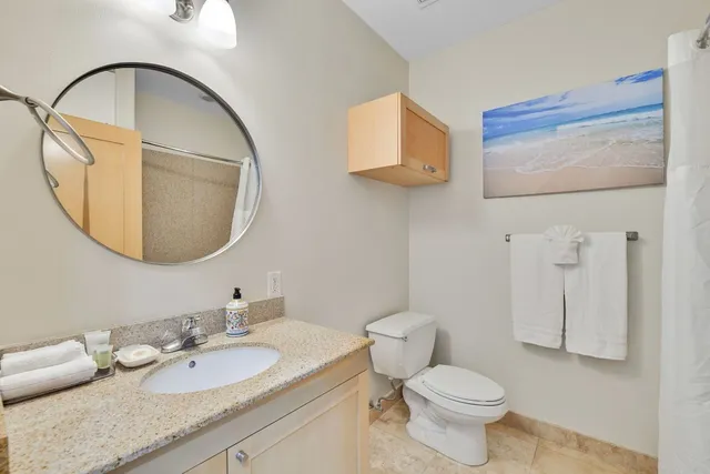 a bathroom with a granite countertop toilet a sink and a mirror