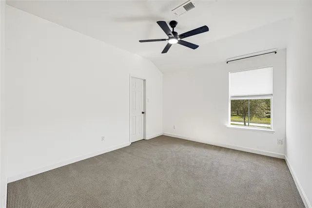 an empty room with a window and a fan