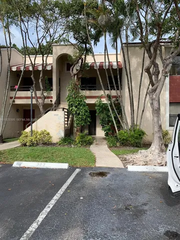 a front view of a house with garden and trees
