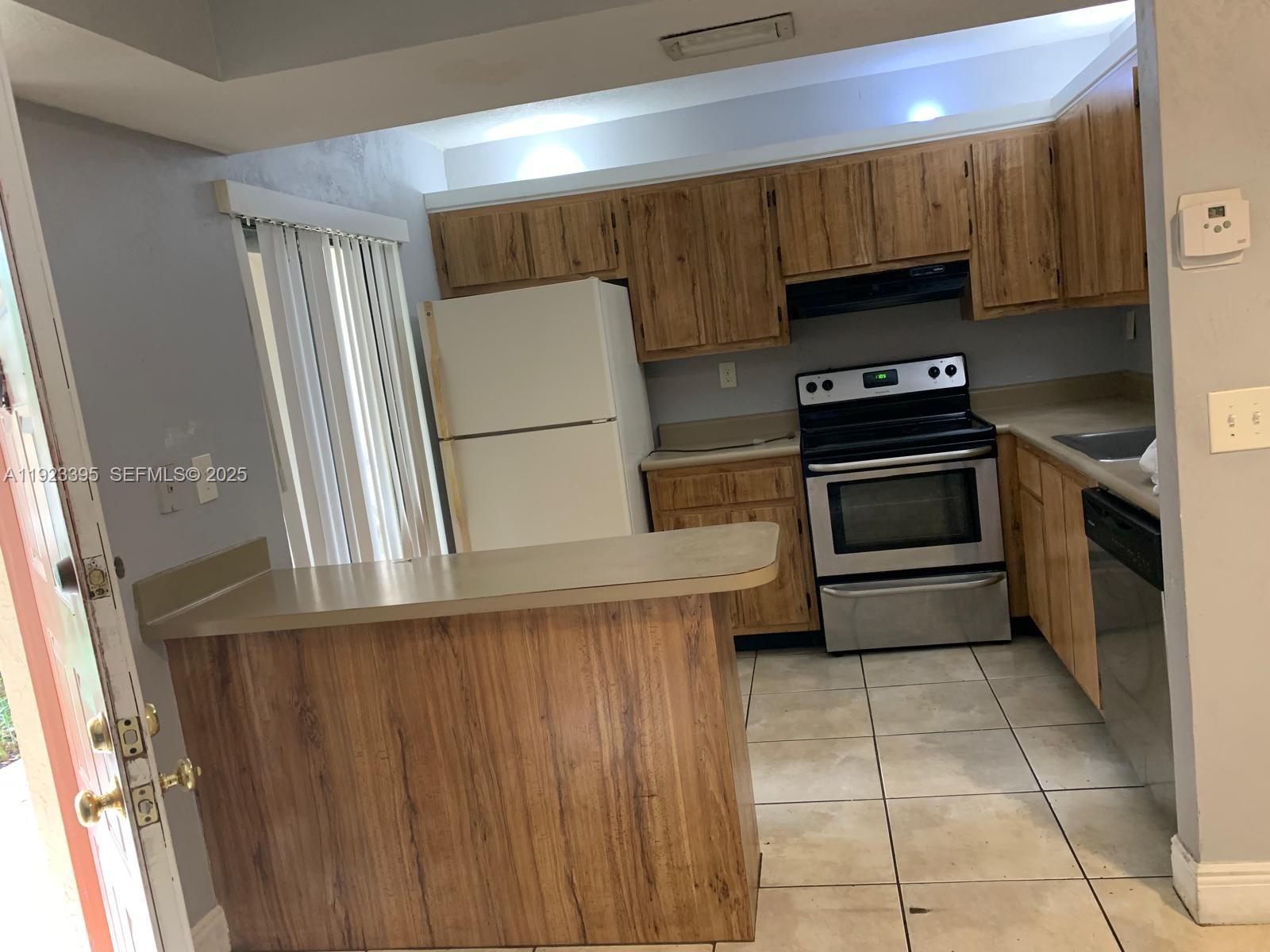 20320 Northeast 3rd Court, Unit 7 Miami, FL 33179 - Photo 9 of 10 a kitchen with a refrigerator a stove a sink and dishwasher