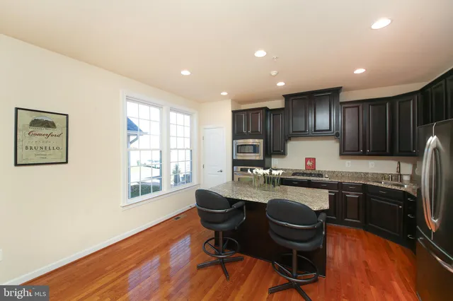 a kitchen with stainless steel appliances granite countertop a sink a stove a refrigerator cabinets and dining table