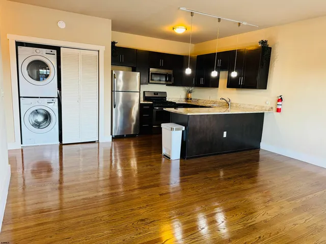 a kitchen with stainless steel appliances granite countertop a refrigerator a stove and a wooden floor