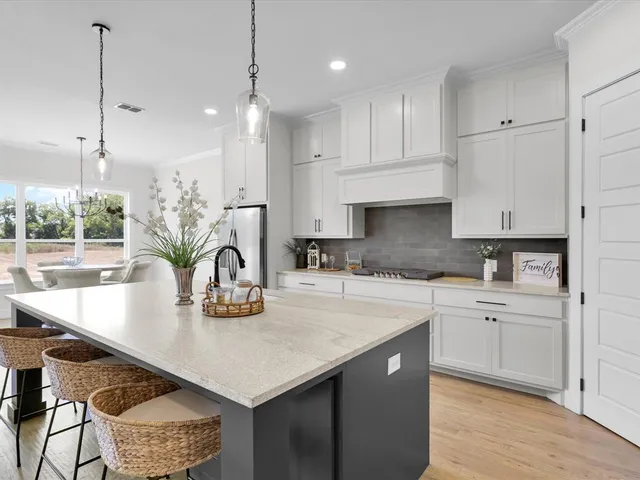 a kitchen with kitchen island granite countertop a table chairs in it and wooden floors