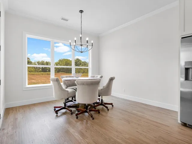 a view of a dining room with furniture a chandelier and wooden floor