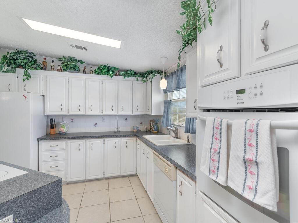 114 Audubon Road Naples, FL 34114 - Photo 11 of 34 a kitchen with granite countertop a sink a stove and cabinets
