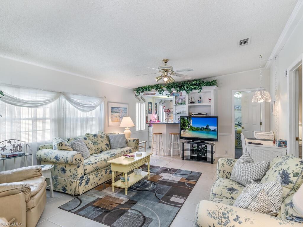 114 Audubon Road Naples, FL 34114 - Photo 13 of 34 a living room with furniture a fireplace and a flat screen tv