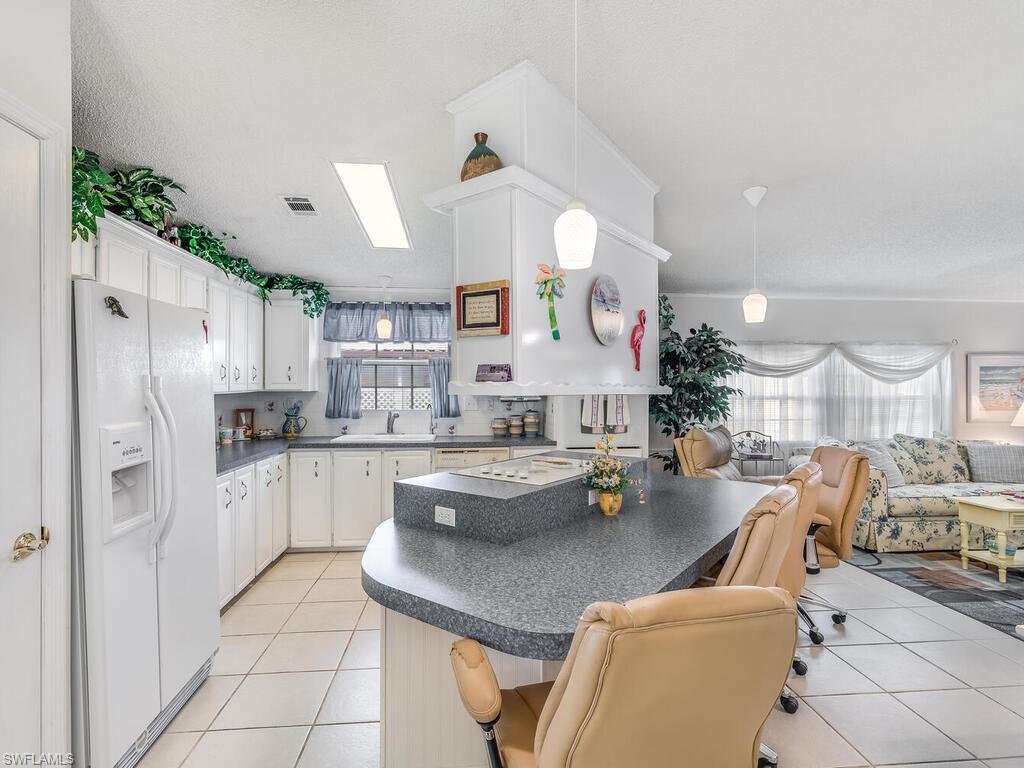 114 Audubon Road Naples, FL 34114 - Photo 10 of 34 a kitchen with stainless steel appliances granite countertop a lot of counter space and living room view