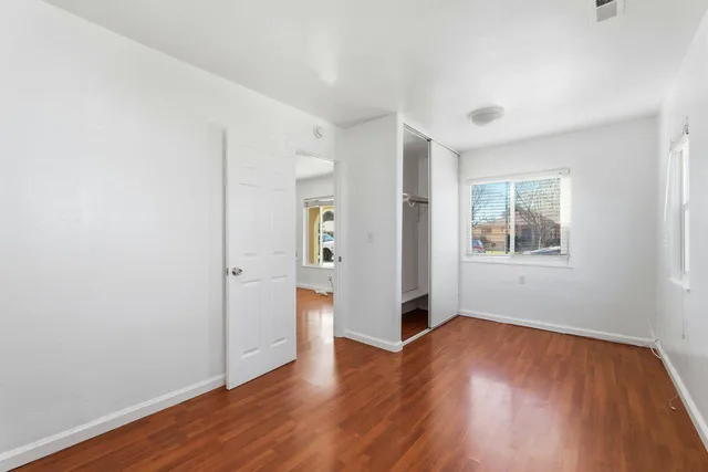an empty room with wooden floor and windows