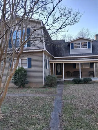 a view of a house with a yard and large tree